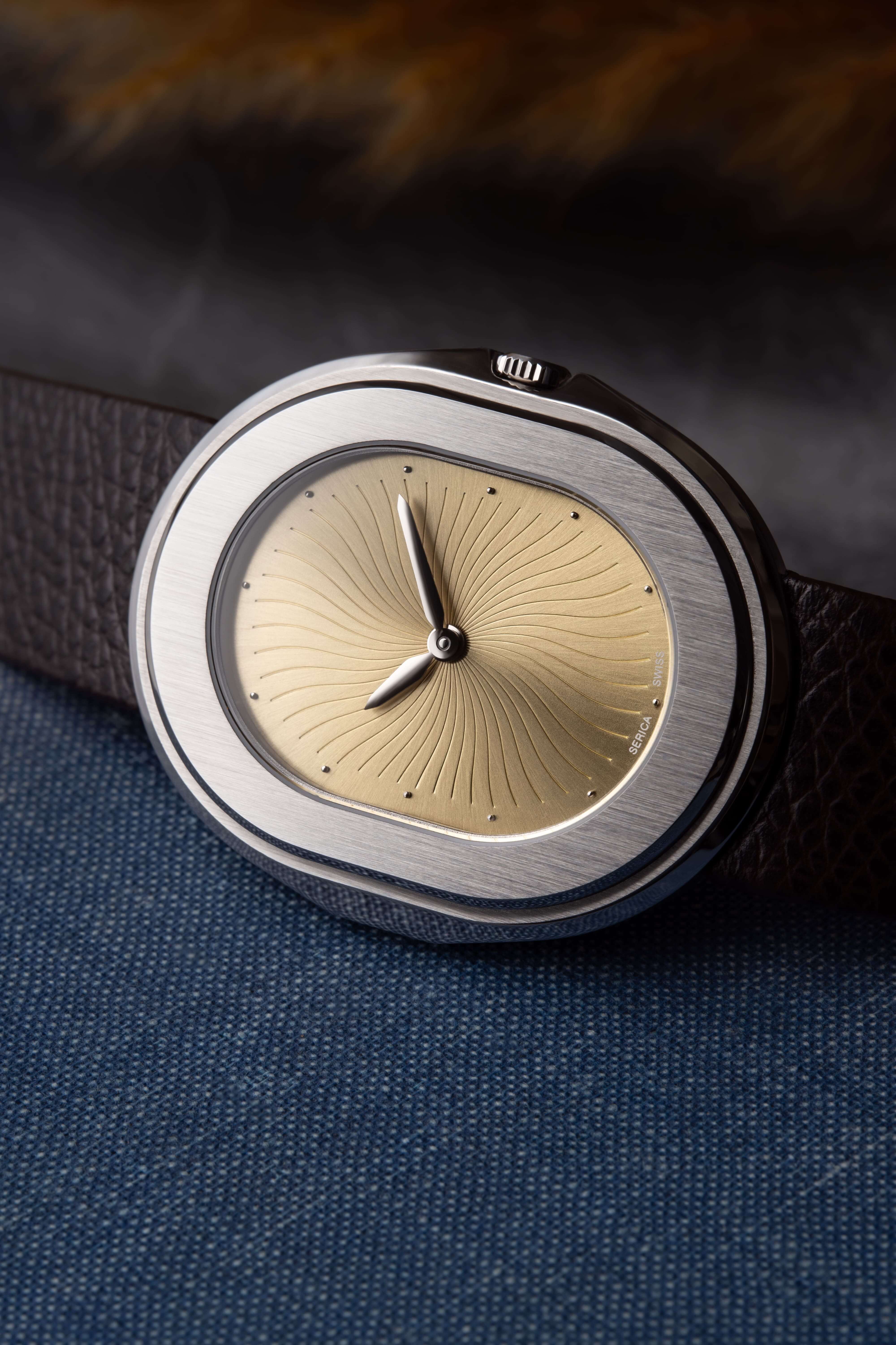Serica Watches - Gros plan sur cadran de montre SERICA 1174-1 Parade automatique. Cadran laiton, boîtier en acier posé sur tissu bleu.