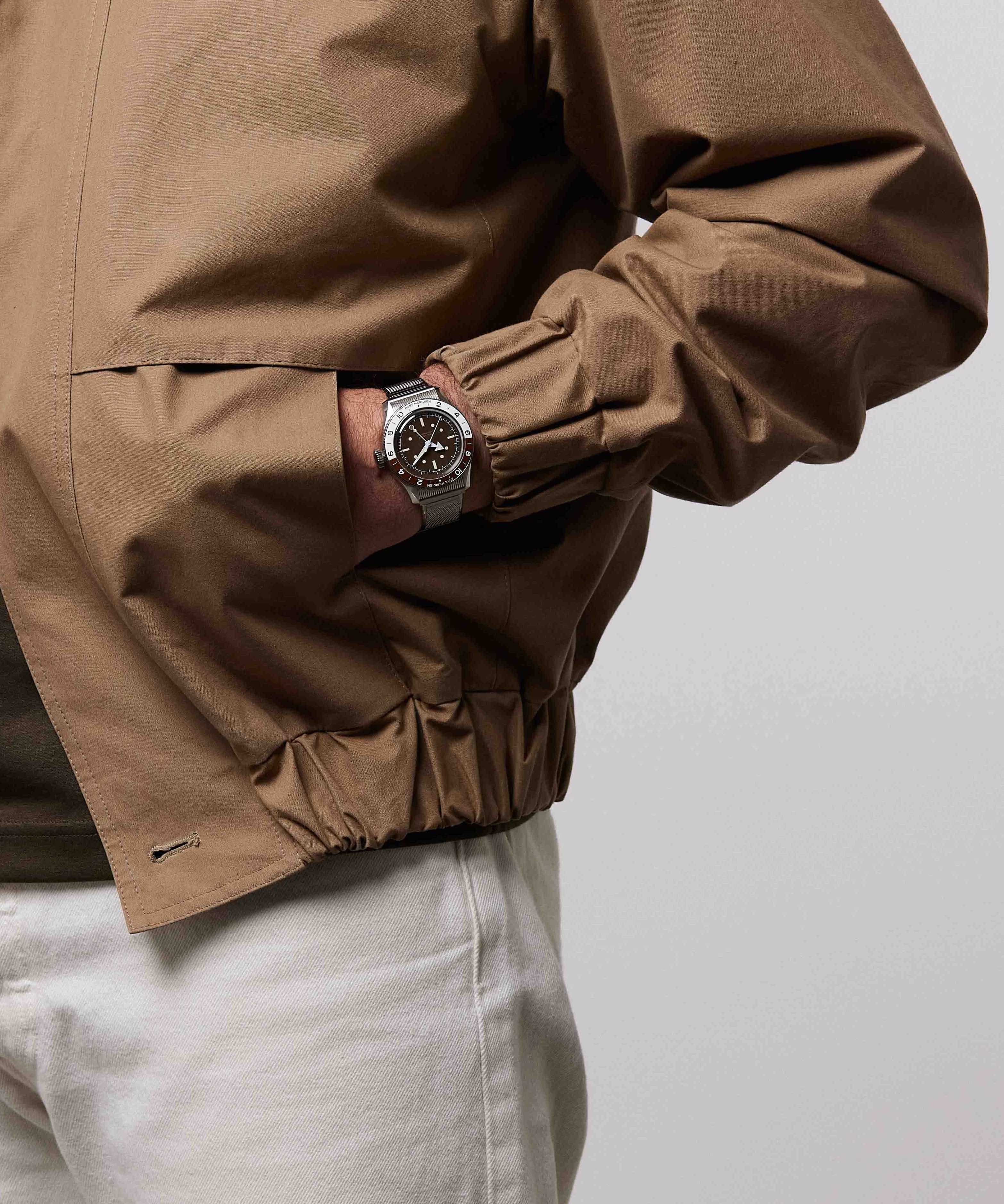 Serica Watches - Plan sur le poignet d'un homme main dans la poche portant la montre SERICA 8315-2 GMT marron avec bracelet en acier.