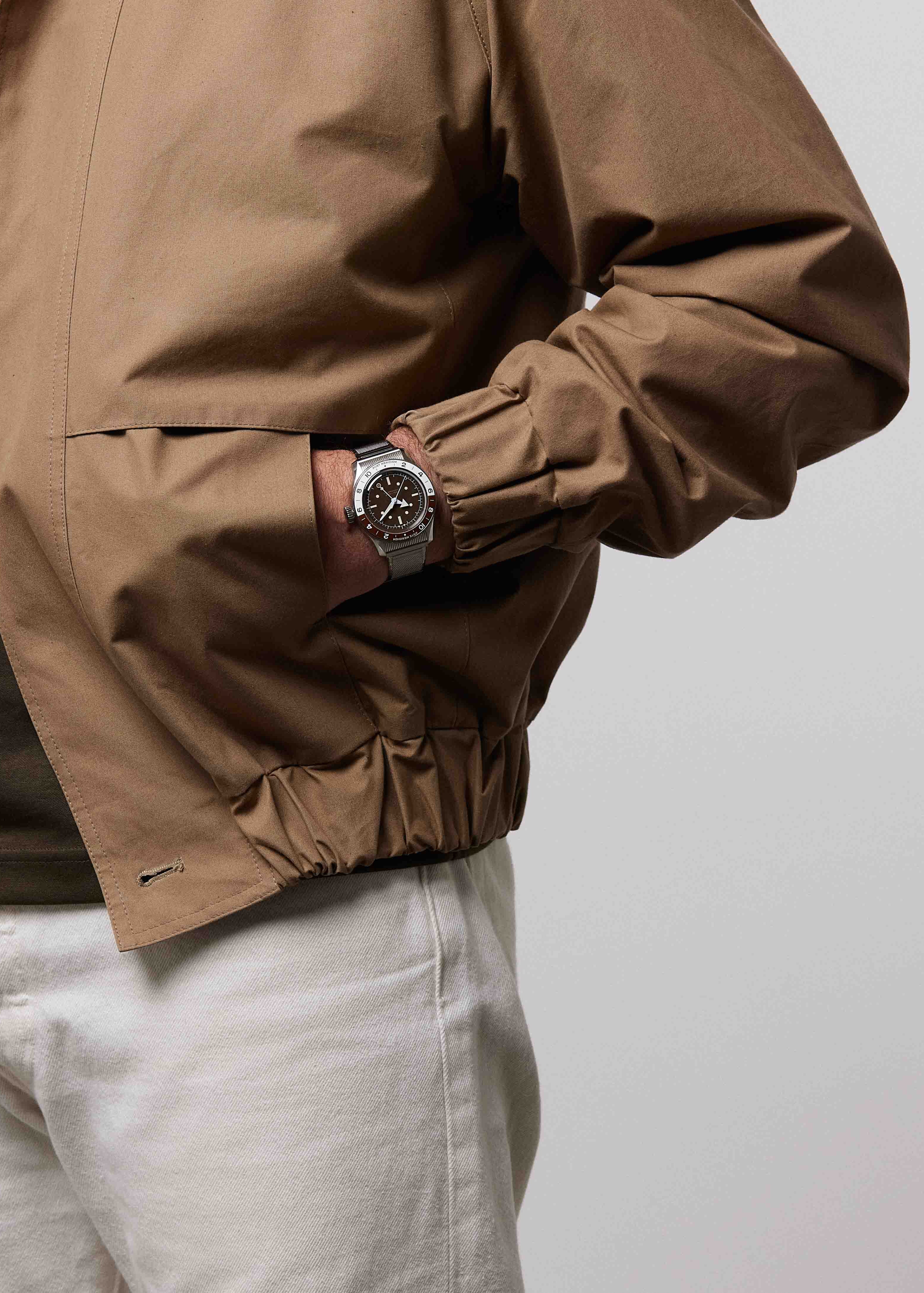 Serica Watches - Plan sur le poignet d'un homme main dans la poche portant la montre SERICA 8315-2 GMT marron avec bracelet en acier.