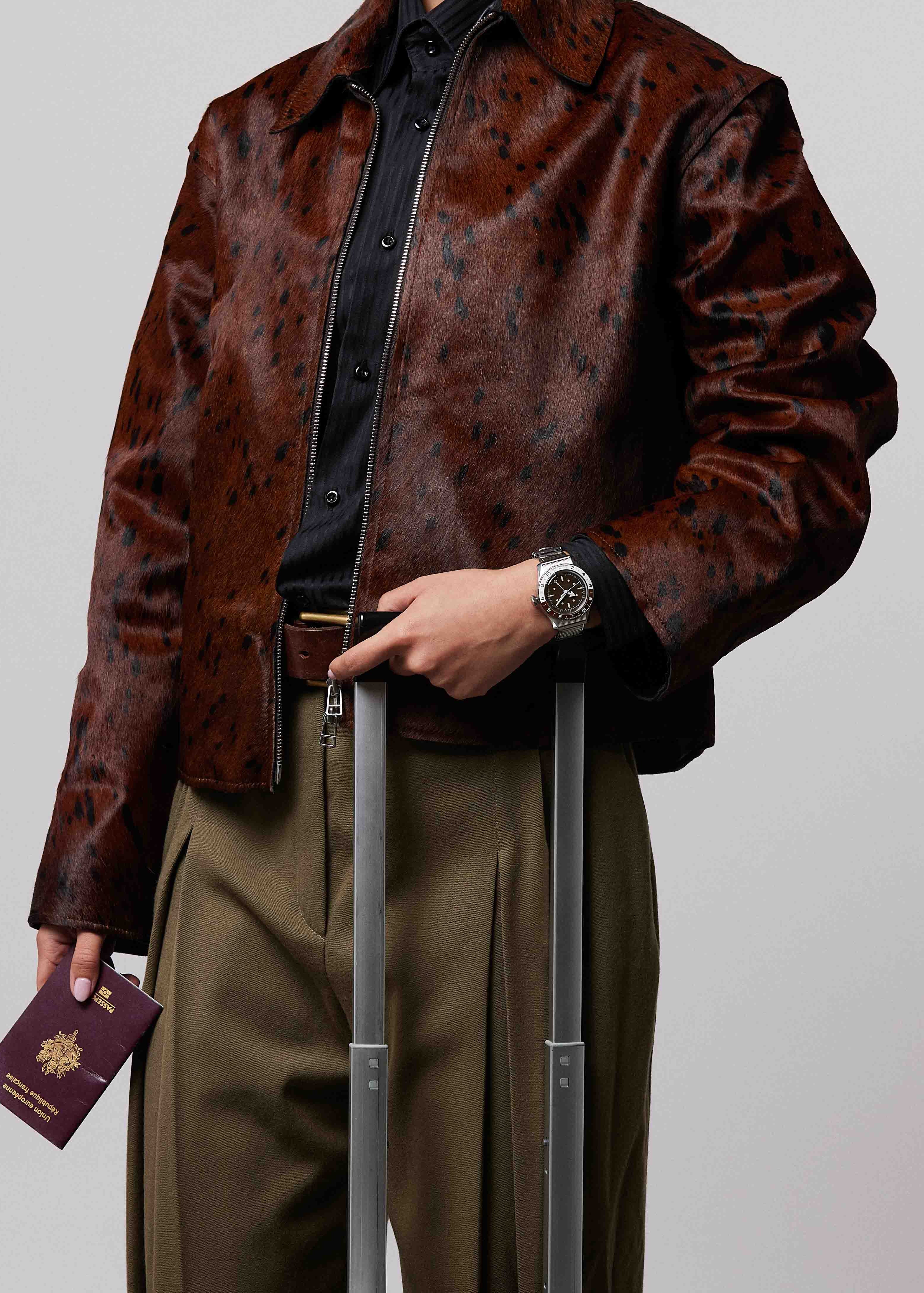 Plan d'une femme tenant une valise valise, portant la montre SERICA 8315-2 GMT marron avec bracelet en acier.