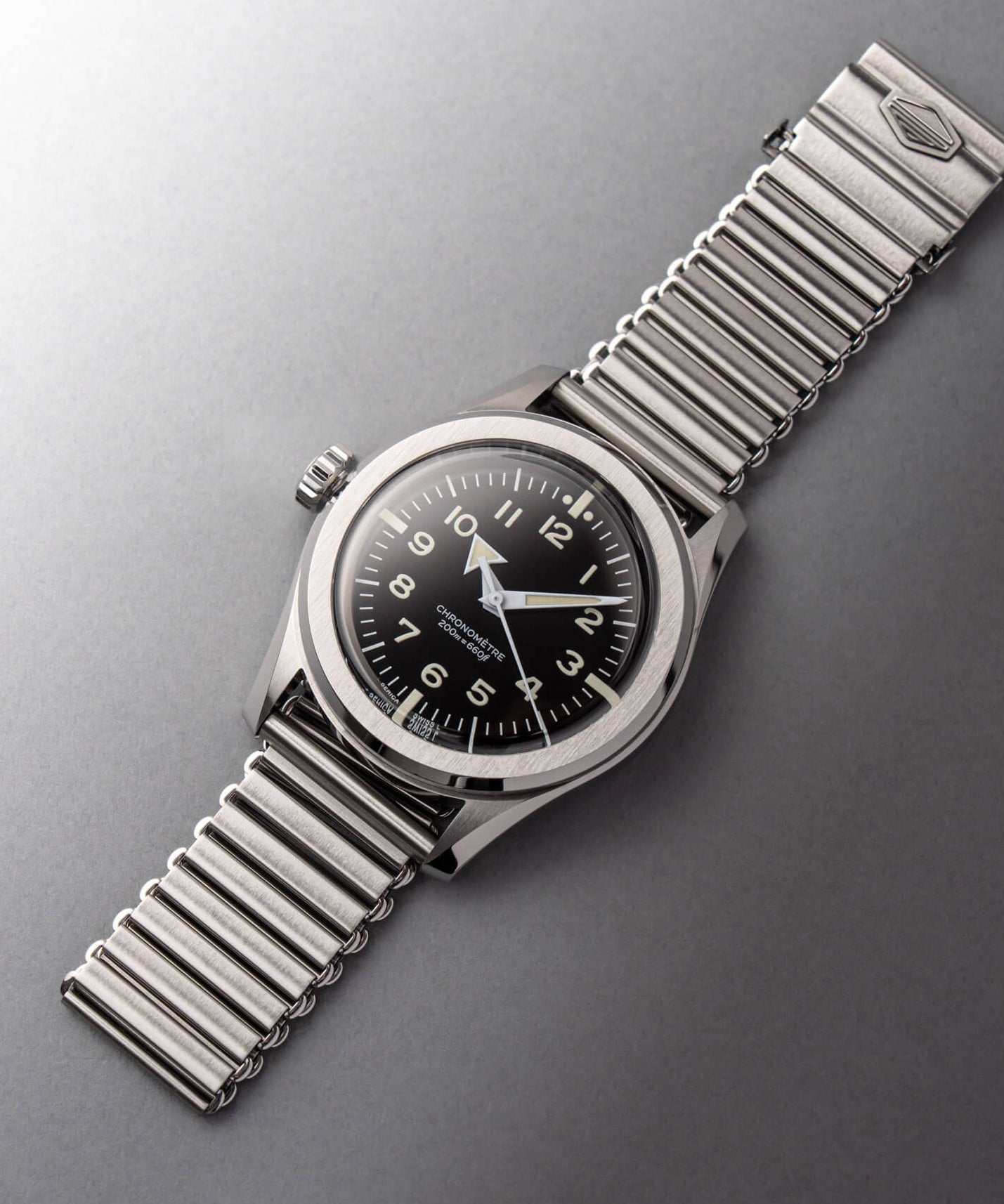 Serica Watches - Nature morte horlogère épurée mettant en scène le chronomètre SERICA 6190 Commando monté sur son bracelet en acier Bonklip.